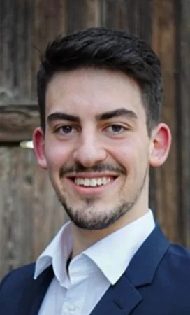 Porträt von Benedikt Pavel vor einer Holzwand.
