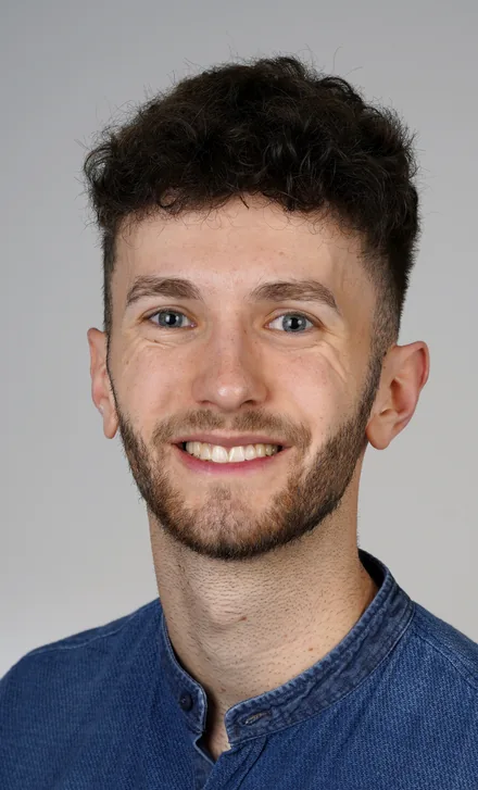 Porträt von Patrick Gröbl vor grauem Hintergrund.